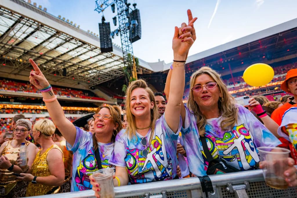 Vrolijke bezoekers met de handen in de lucht vooraan bij het podium